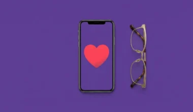 Smartphone showing a heart next to a pair of reading glasses on a purple background